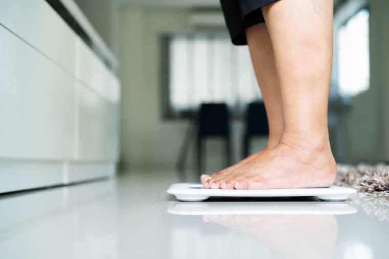 old woman standing on weight scale in living room