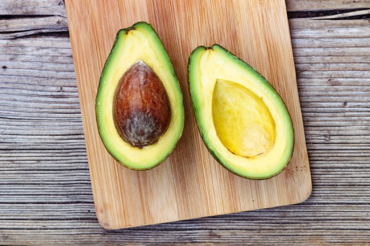 A ripe avocado fruit on a rustic table, closeup, top view