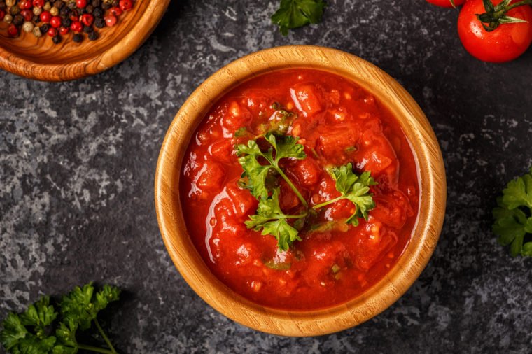 Tomato sauce with garlic and parsley in a wooden bowl, top view.