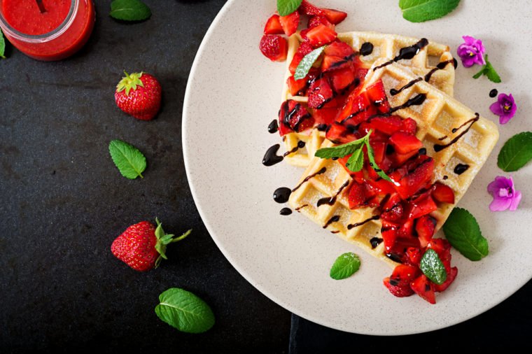 Belgium wafers with strawberries, chocolate and syrup on a plate. Flat lay. Top view