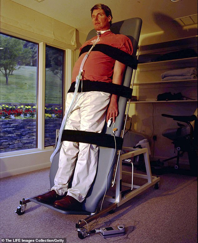 Christopher on a tilt table accustoming his body to being upright, therapy in hopes of being able to walk again, at his summer home