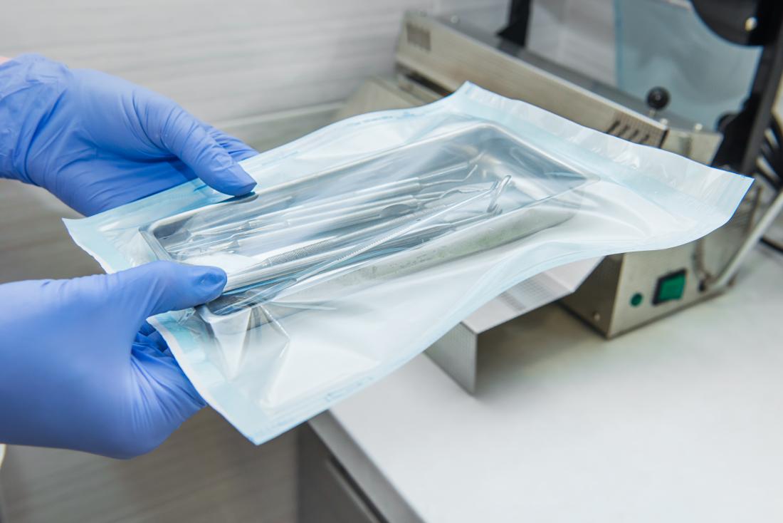 Person with gloved hands holding vacuum sealed bag of sterilized medical equipment