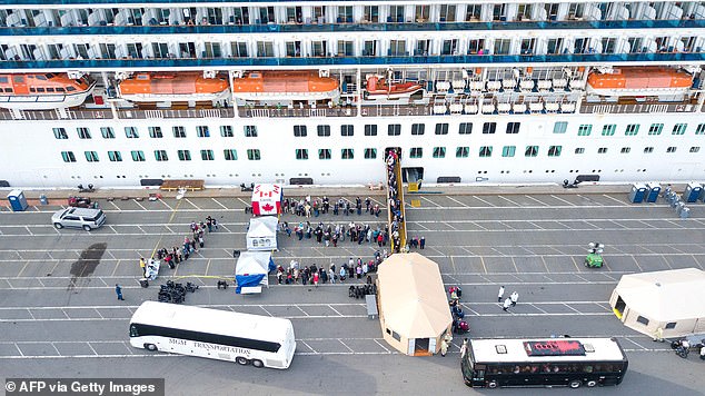 Canadian passengers disembark and line up behind tents denoted with the country's flag on Monday after the 21 infected passengers were removed. Canadian citizens will be repatriated back home
