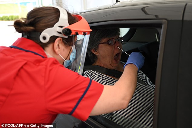But some testing centres appear to have ditched this approach and are now requiring symptomatic people to do to the tests - which are already prone to giving false negatives - themselves. Pictured: A health worker takes a swab to test a key worker at Royal Papworth Hospital in Cambridge on May 5, 2020
