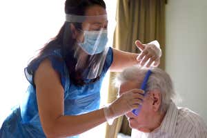 A care worker wearing full Personal Protection Equipment (PPE) as she goes about her job