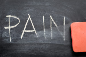 A red eraser erasing the word "pain" written in chalk