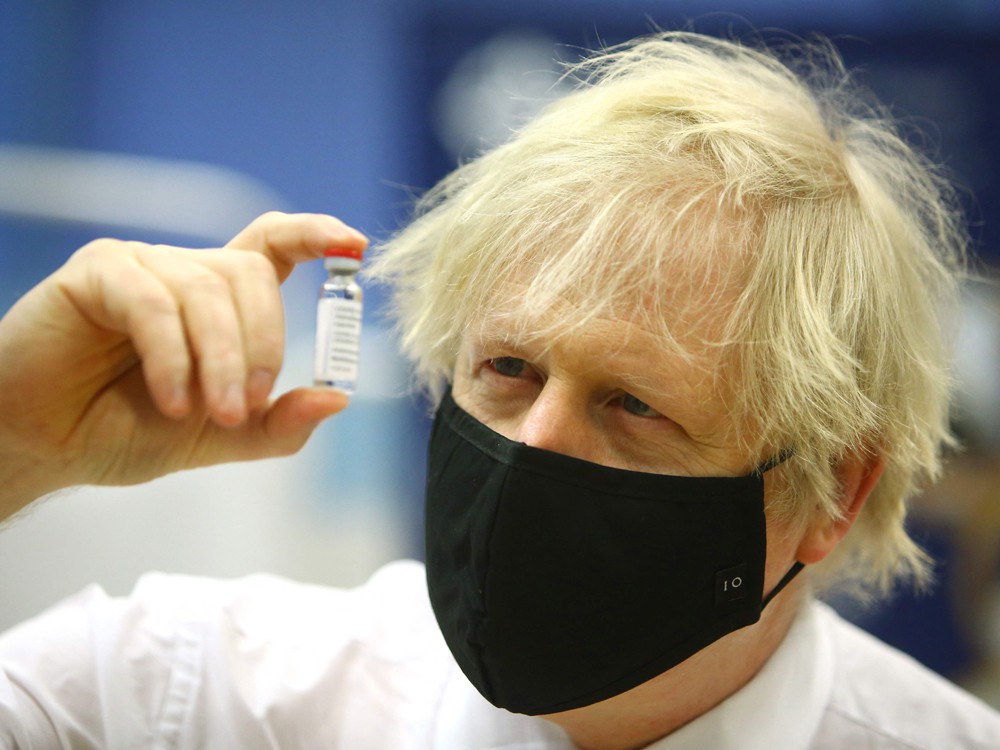 Britain's Prime Minister Boris Johnson poses with a vial of the Oxford/AstraZeneca vaccine as he visits a vaccination centre at Cwmbran Stadium in Cwmbran, south Wales on Feb. 17, 2021.