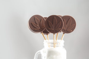 Cannabis edibles shaped as chocolate lollipops for medical or recreational consumption; cannabis lollipops in jar